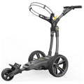 A golf trolley stands upright with three large wheels and a handle. The trolley is designed for transporting golf clubs, featuring a sleek modern design intended for outdoor use on golf courses.