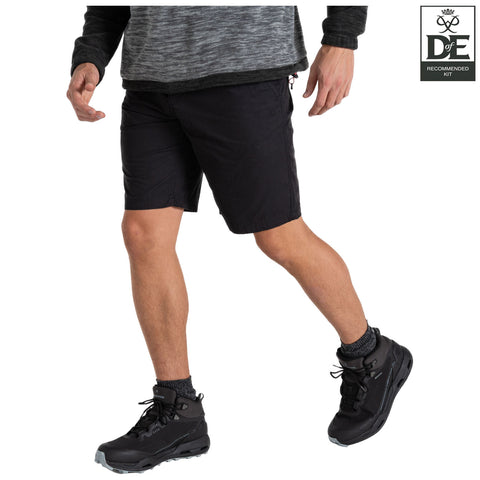 A person is walking in black shorts and high, sturdy boots with ankle support. The setting suggests an outdoor, active environment with a focus on functionality and comfort.