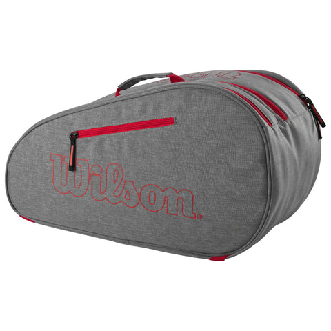 A gray sports bag with red zippers and detailing is positioned at an angle. The bag features the logo "Wilson" prominently displayed in red on its side.