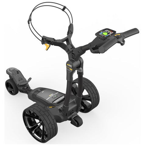 A black electric golf trolley stands upright with two large wheels and a smaller front wheel displaying a digital control panel and handlebars indicating its advanced functionality in a white background setting.