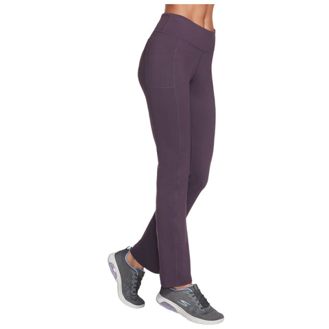 Fitted purple leggings are displayed standing upright with a model wearing gray athletic shoes in a neutral environment highlighting the garment’s shape and design.