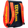 A red and black sports bag features the Wilson logo prominently in yellow. The bag is zipped and has a handle, designed for carrying sports equipment or gear.