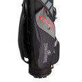 A golf bag stands upright featuring multiple compartments and a prominent logo The bag is designed for carrying golf clubs and accessories in outdoor settings