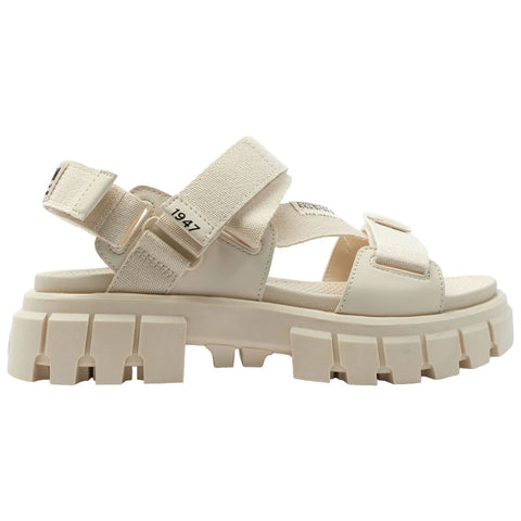 A chunky beige sandal features wide adjustable straps and a thick textured sole, designed for comfort and style, suitable for casual outdoor wear or urban environments.