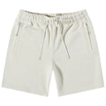 Light-colored shorts made of soft fabric are displayed flat. They feature an elastic waistband with a drawstring and side pockets. The brand name is subtly printed on the leg.