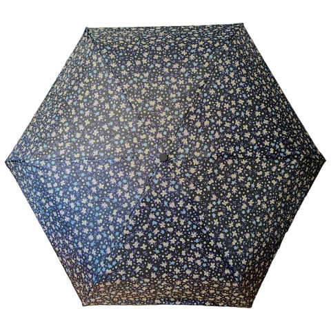 A hexagonal umbrella is open displaying a black fabric adorned with small, colorful floral patterns, providing protection from the elements in an outdoor or rainy environment.