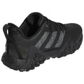 A black athletic shoe features a textured upper and a rugged sole with prominent treads designed for traction, positioned against a white background suggesting a product display or advertisement.