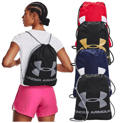 A black drawstring backpack featuring a large logo is worn by a person in pink shorts while several other colorful backpacks are displayed behind in a retail context.