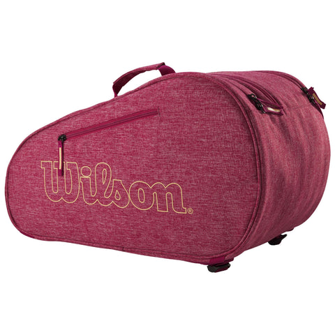 A red sports bag displays the logo "Wilson" prominently The bag features a rounded shape and a zippered compartment designed for carrying sports equipment in a casual setting