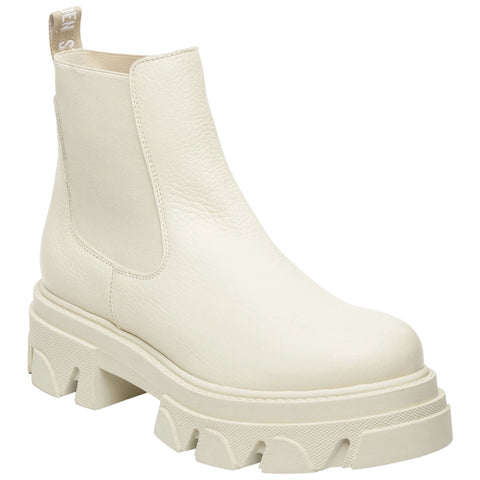 A white Chelsea boot features a chunky sole with ridged details and elastic side panels designed for easy wear in fashion-forward contexts. A tab at the back aids in slipping on.