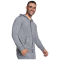 A man in a gray zip-up hoodie smiles and gestures, standing confidently in a neutral background, showcasing casual athletic wear suitable for relaxed or active settings.