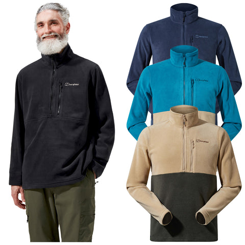 A man with a beard is wearing a black fleece pullover with a zip at the collar while smiling. Behind him are three additional fleece pullovers in various colors.