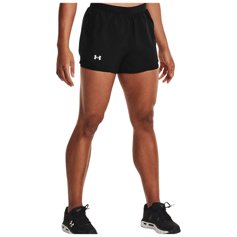 Black athletic shorts are worn by a person standing upright with one hand on their hip in a neutral indoor setting. The individual is wearing black athletic shoes.