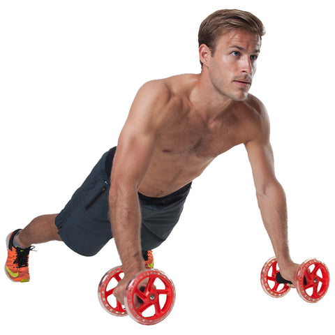 A shirtless man performs an exercise using red wheel push-up handles while positioned in a plank on a plain background, focusing intently ahead.