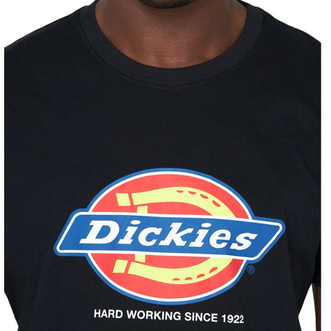 A black t-shirt displays a colorful logo with the word "Dickies" prominently featured along with the text "HARD WORKING SINCE 1922" underneath in a casual setting.