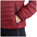 A red insulated jacket is being worn with a hand inserted into the side pocket while the other arm is bent at the elbow, suggesting a casual and comfortable stance.