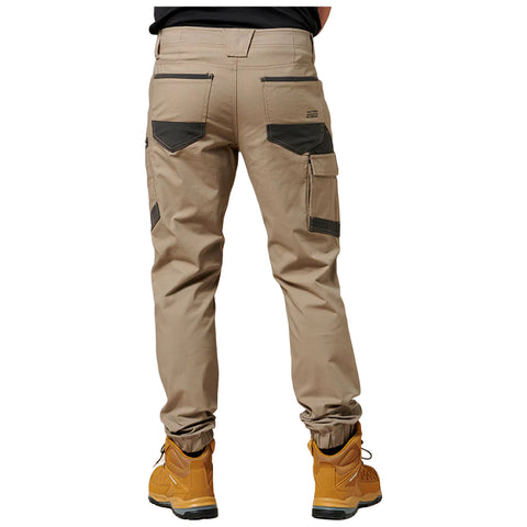 Beige cargo pants with multiple pockets and knee reinforcements are worn by a person. They are standing in sturdy yellow work boots, suggesting a practical outdoor context.