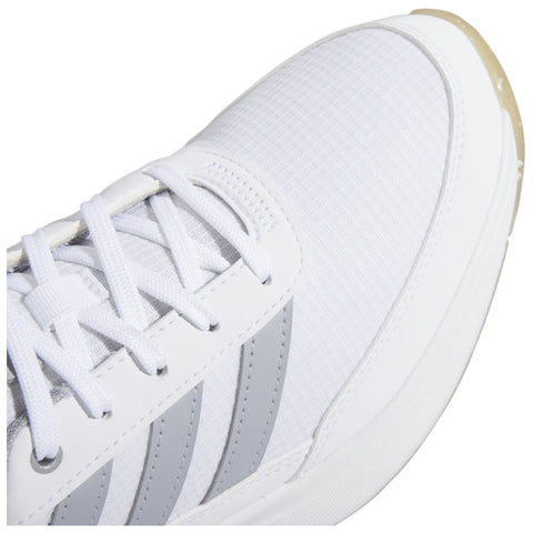 A white sneaker with a textured surface and gray stripes is positioned prominently with laces threaded through eyelets while casting a light shadow on a plain background.