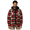 A man stands wearing a red and black plaid flannel shirt over a black hoodie with a neutral background, conveying a casual and stylish appearance.