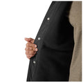 A hand grips the inside of a black jacket while the outer layer is slightly opened revealing a soft lined interior suggesting an action of adjusting or putting on the garment.