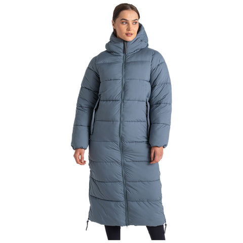 A long blue puffer coat with a hood is worn by a woman standing with a neutral expression the coat features a zipped front and is padded for warmth in a plain background.