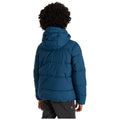 A child is standing with their back to the viewer wearing a blue puffer jacket with a hood in a neutral background. The child's hands are relaxed at their sides.