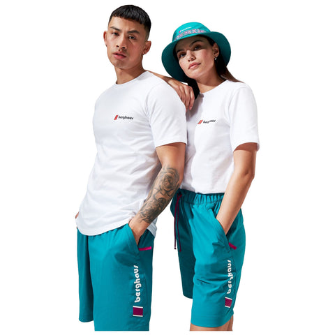 A man and a woman stand closely together in casual clothing. The man wears a white t-shirt and turquoise shorts while the woman wears a similar t-shirt and matching shorts. They display a relaxed pose.