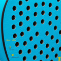 A blue textured surface features numerous black perforations. The object appears to be a paddle or sporting equipment with specifications nearby including thickness and weight plus material details.