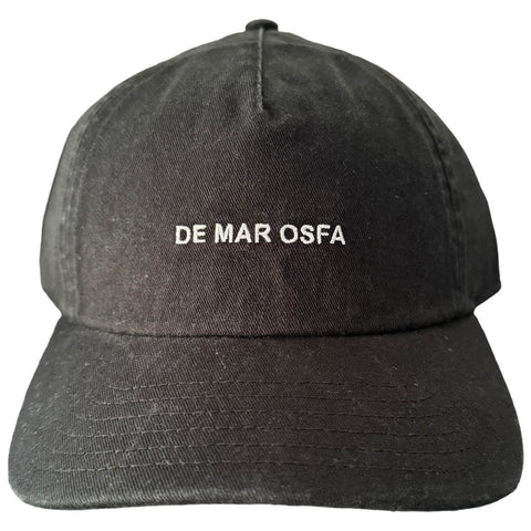 A black baseball cap features the embroidered text "DE MAR OSFA" on its front, positioned with the brim facing downward, set against a neutral background.