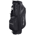 A black golf bag stands upright featuring multiple compartments for storing clubs and accessories showcasing a logo prominently while being likely prepared for a round of golf on a course.