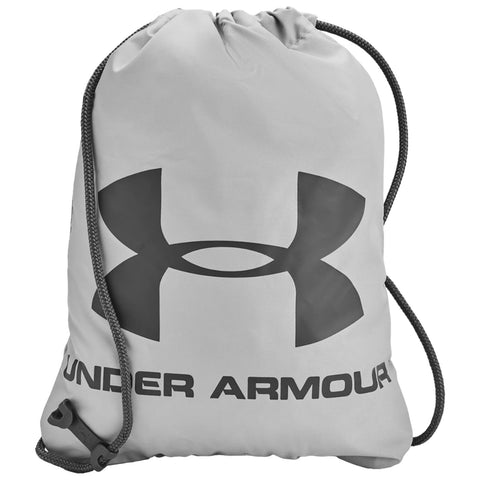 A gray drawstring backpack sits upright featuring a large black Under Armour logo and brand name at the bottom with a closure mechanism on the side used for securing contents.