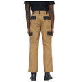 Tan cargo pants are worn by an individual facing away. The pants feature multiple pockets and black patches on the back. The person stands on a plain background.