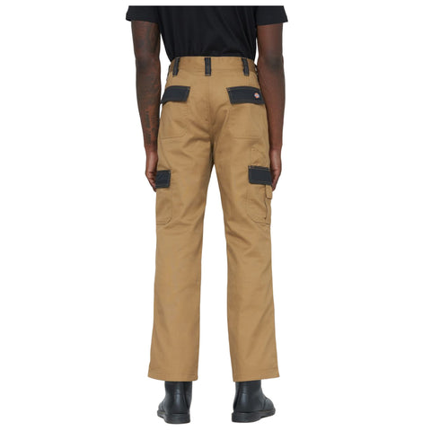 Tan cargo pants are worn by an individual facing away. The pants feature multiple pockets and black patches on the back. The person stands on a plain background.