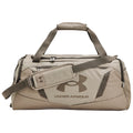 A tan duffel bag with a prominent Under Armour logo sits vertically featuring a top handle and a detachable shoulder strap suggesting it is used for carrying sports or gym equipment.