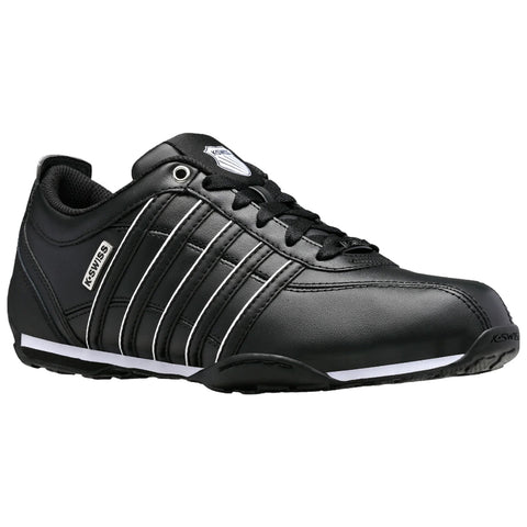 A black athletic shoe features a sleek design with white stripes and a logo on the side. It rests on a flat surface against a neutral background.