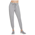 Gray sweatpants with an elastic waistband and drawstring are being worn by a person standing. The context suggests a casual or athletic setting. They are paired with gray athletic shoes.