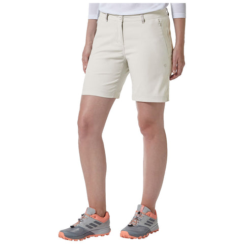 A person stands wearing beige shorts and gray-orange athletic shoes facing away from the viewer in a neutral environment, suggesting a casual outdoor activity or setting.