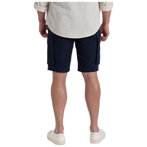 A person stands facing away wearing a light-colored shirt and navy cargo shorts with side pockets in a casual setting, complemented by white shoes on their feet.