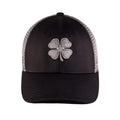 A black cap features a prominent embroidered gray four-leaf clover logo on the front with a structured crown and a curved brim designed for casual outdoor wear.