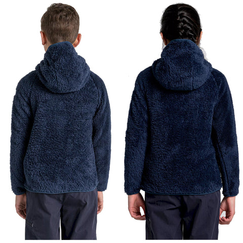 Two children are standing back-to-back wearing navy blue fleece jackets with hoods Their arms are relaxed at their sides against a plain white background