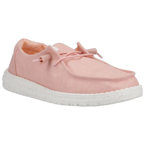 A pink shoe with a soft fabric upper sits on a flat surface featuring a white textured sole and light laces, suggesting comfort and casual style.