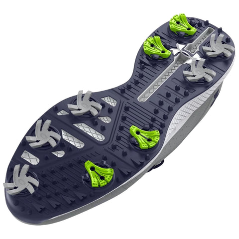 A shoe sole with distinct multi-directional studs and spikes is positioned flat displaying a gray and black design with bright green accents suitable for athletic performance on grass or turf surfaces