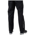 Black waterproof pants are standing vertically with a person’s legs visible while wearing black shoes the pants feature zippers at the ankles and a brand logo along the side