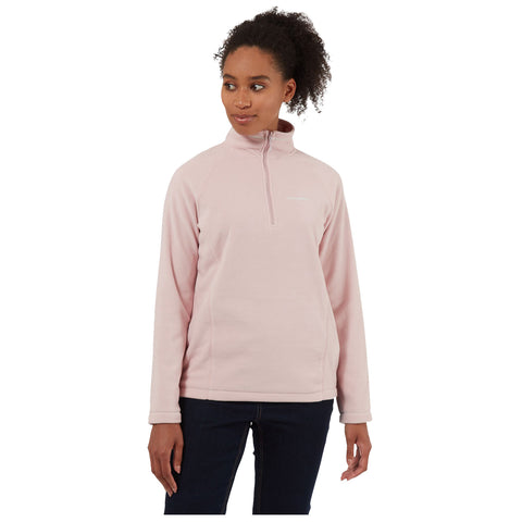 A woman stands wearing a light pink fleece pullover with a zippered collar she gazes to her left in a neutral setting suggesting casual wear for cool weather.