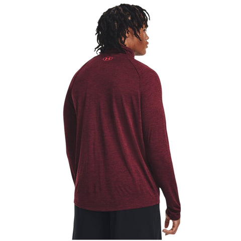 A person wearing a maroon long-sleeve shirt stands with their back to the viewer, showcasing the shirt's collar and a logo on the upper back in a neutral background.