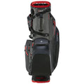 A golf bag stands upright featuring multiple zippered pockets and a sturdy base the bag is primarily black with red accents designed to securely hold golfing equipment and accessories