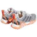 Gray and white athletic shoes feature a textured mesh upper with orange accents and a distinct sole pattern designed for grip in various environments. The shoes are positioned from a rear view.