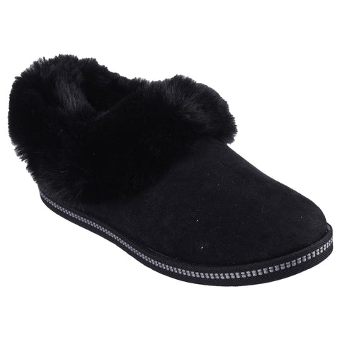 A black slipper features a soft fur cuff and a sturdy sole suggesting comfort and warmth suitable for indoor use often seen in cozy home environments.