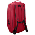 A red backpack stands upright displaying padded shoulder straps and a top handle while featuring a logo and design elements that suggest a sporty, functional style for carrying equipment.