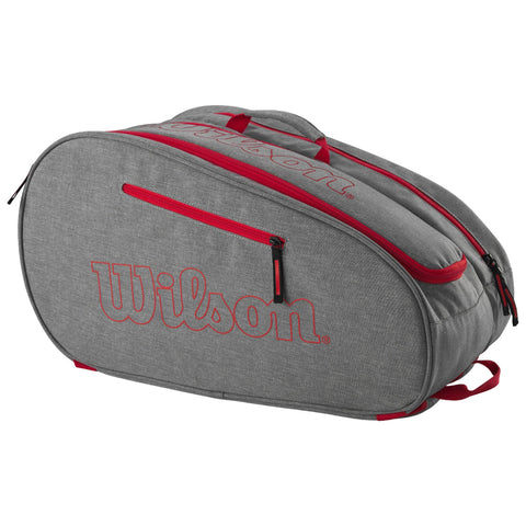 A gray athletic bag with red zippers and accents is positioned on a flat surface showcasing its sleek design and the prominent embroidered logo reading Wilson on the side.